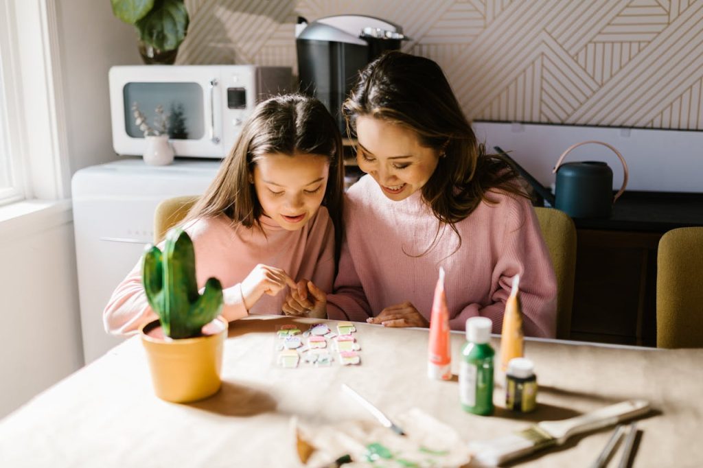 A mother and daughter enjoy quality time together painting at home, promoting creativity and bond.
